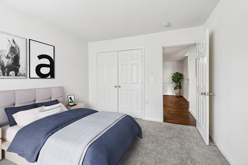 A bedroom with a bed, a nightstand, and a plant.