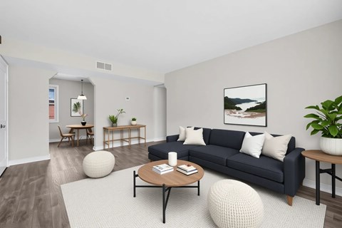 A living room with a black couch, a coffee table, and a large painting on the wall.