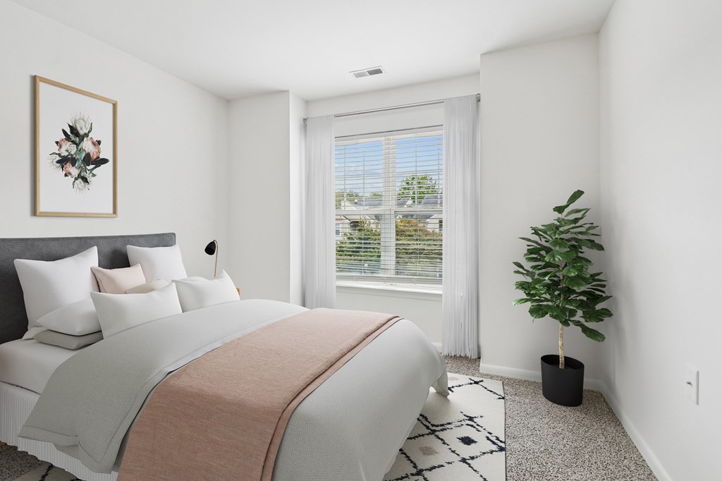 A bedroom with a large bed and a potted plant.