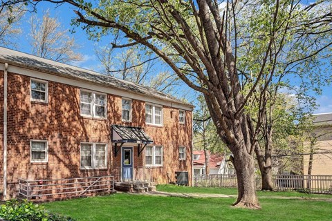 A red brick building with a tree in front at Highland Ridge Apartments, Maryland, 20743