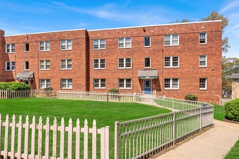 A red brick building with a white picket fence in front at Highland Ridge Apartments, Capitol Heights, Maryland