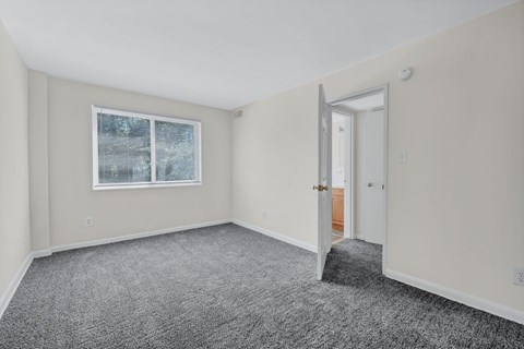 A room with a carpeted floor and a window with blinds at Highland Ridge Apartments, Capitol Heights, MD