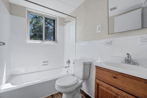 A white toilet sits next to a white sink in a bathroom at Highland Ridge Apartments, Maryland