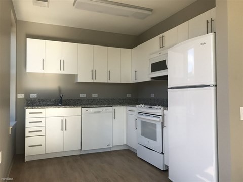 A kitchen with white appliances and cabinets.