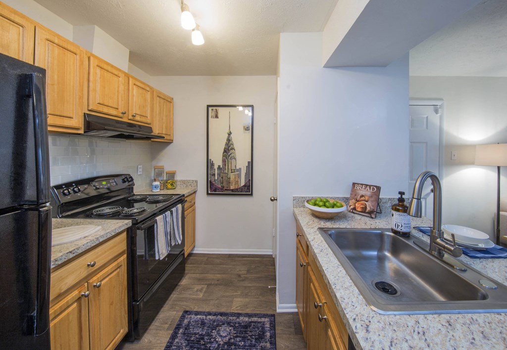 a kitchen with wood cabinets and black appliances at Madison at Eden Brook, Maryland, 21046