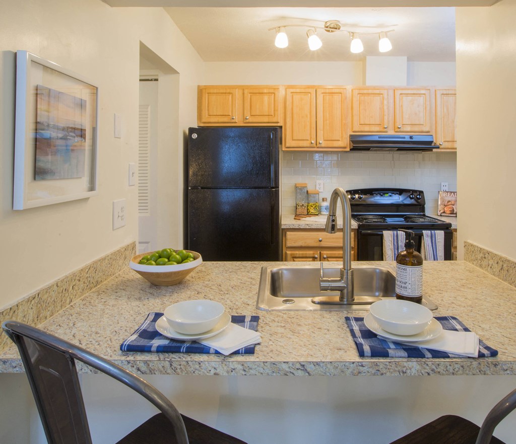 a kitchen with a black refrigerator freezer next to a stove top oven at Madison at Eden Brook, Columbia