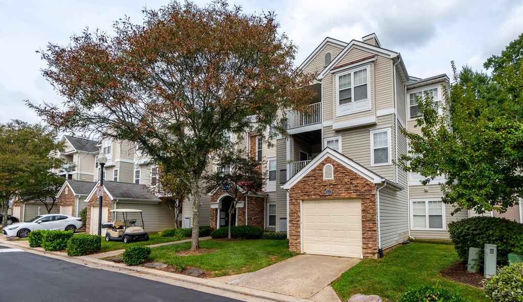 A residential street with apartment buildings and parked cars.