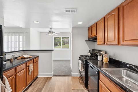 A kitchen with wooden cabinets and black countertops.
