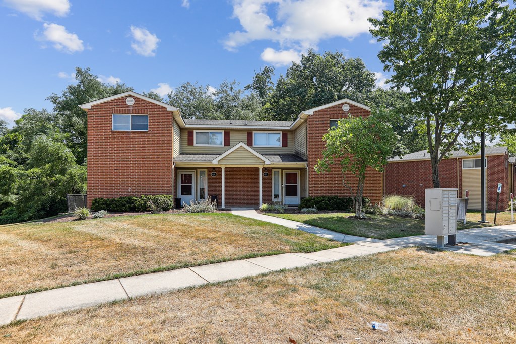 the front of a brick house with a lawn and trees at Villages at Morgan Metro, Maryland, 20785