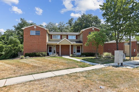 the front of a brick house with a lawn and trees at Villages at Morgan Metro, Maryland, 20785