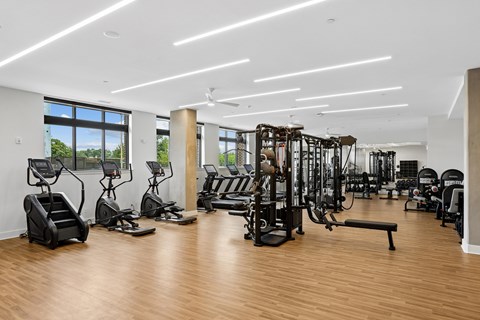 A gym with a variety of equipment including treadmills, weights, and exercise machines.