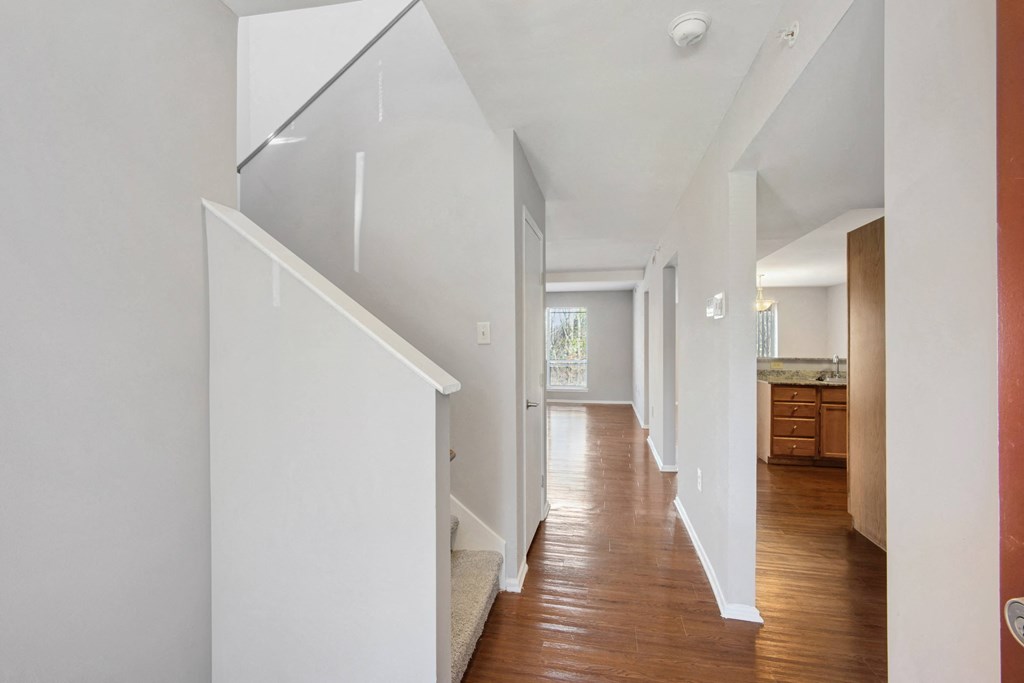 a hallway with white walls and a staircase with wood floors at Villages at Morgan Metro, Landover, MD