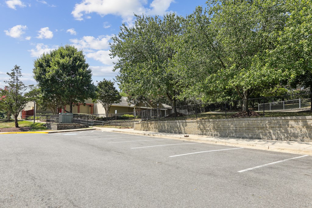 an empty parking lot with trees and a building in the background at Villages at Morgan Metro, Landover, MD