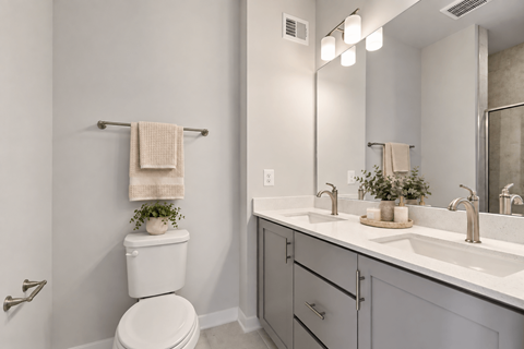 A white toilet is in a bathroom with a white sink.