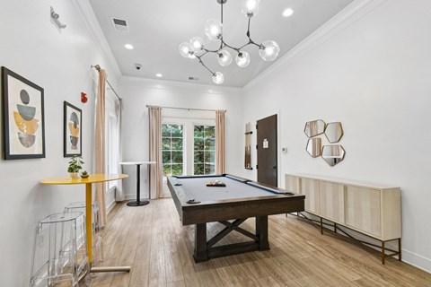 A pool table is in the middle of a room with a yellow table and a chandelier  at Poplar Glen Apartments, Columbia, MD, 21044.