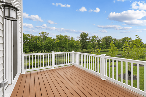 A wooden deck with a white railing and a white door.