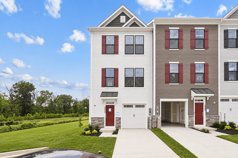 A modern two-story apartment building with a red door and garage door.