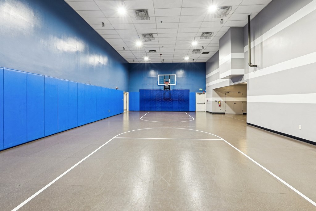 a basketball court in a large room with blue walls and a white scoreboard at Villages at Morgan Metro, Landover, Maryland