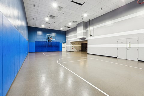 a basketball court in a gym with a blue wall and white doors at Villages at Morgan Metro, Landover, MD