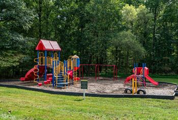 A playground with a red and yellow slide and a red and blue swing set at Park at Winterset Apartments, Owings Mills, Maryland