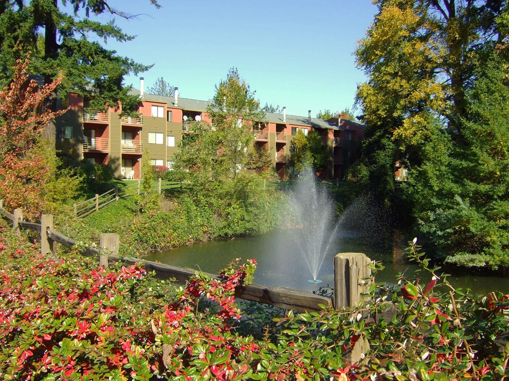 a fountain in a pond with a building in the background