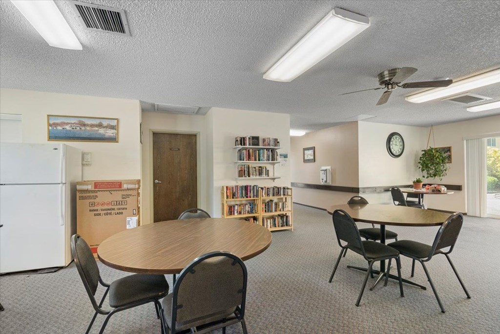 A room with a table, chairs, and a bookshelf.