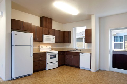 an empty kitchen with white appliances and wooden cabinets