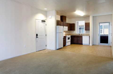 an empty living room and kitchen with a refrigerator and a sink