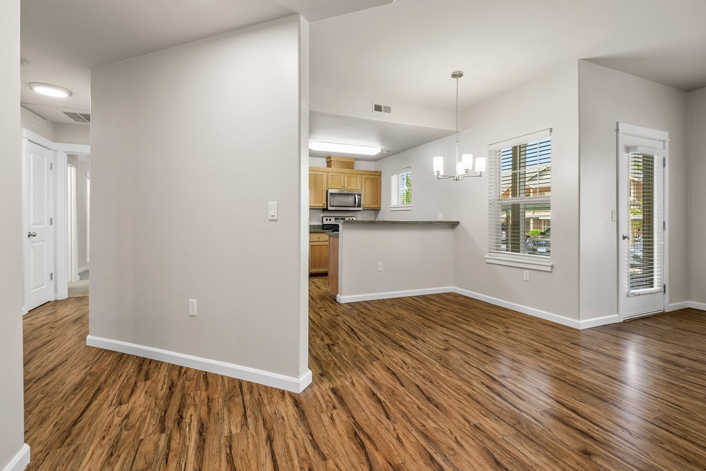 an empty living room and kitchen with wood flooring