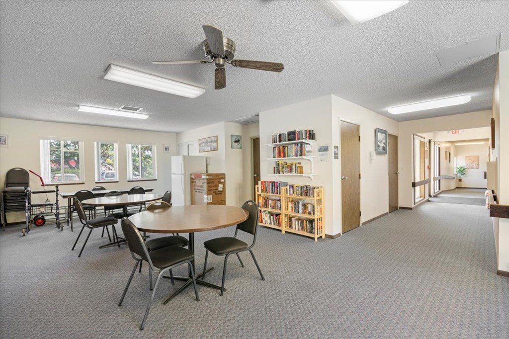 A room with a table, chairs, and a ceiling fan.