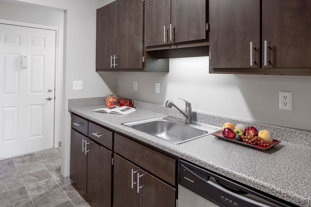 a kitchen with dark cabinets and a stainless steel sink