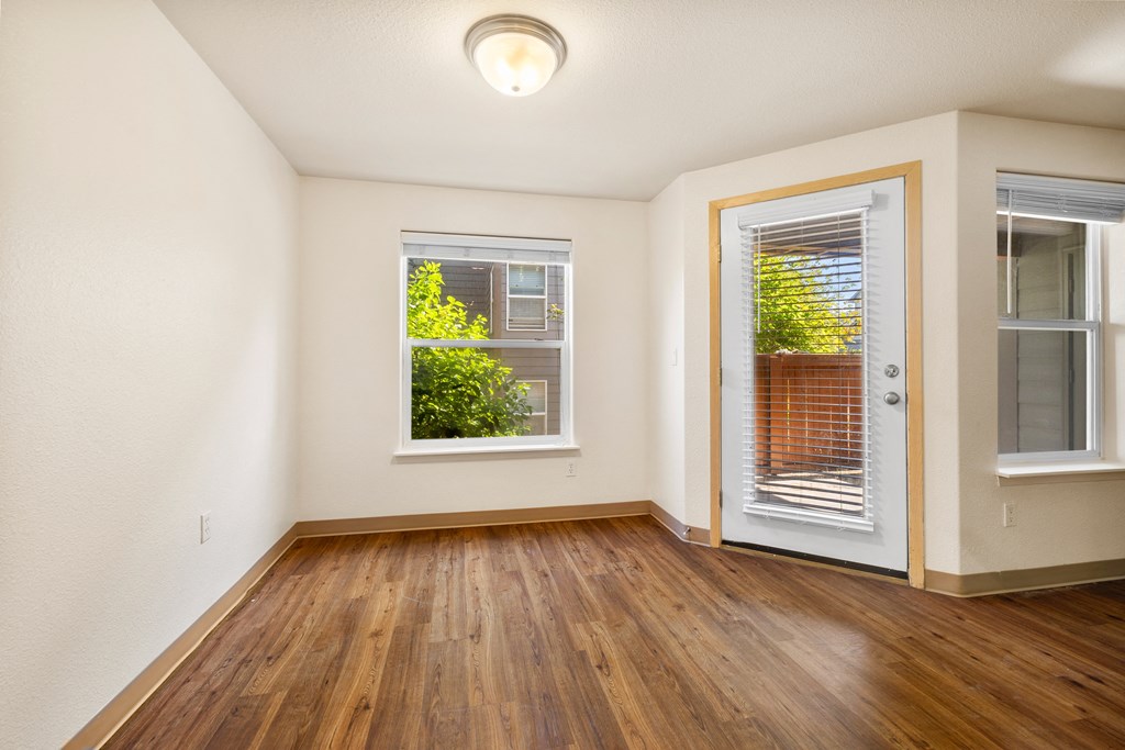 an empty living room with wood floors and a door to a balcony