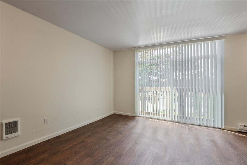 A room with wooden floors and a window with blinds.