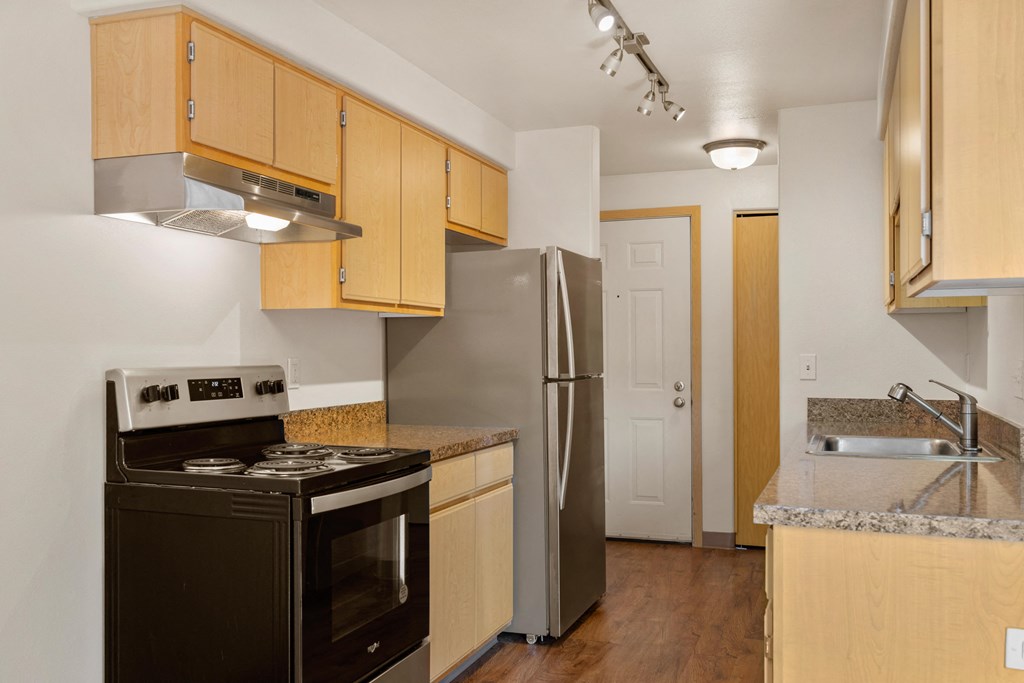 a kitchen with wood cabinets and stainless steel appliances and a refrigerator