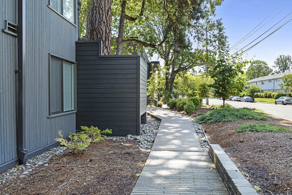 A modern house with a grey exterior and a small garden in front.