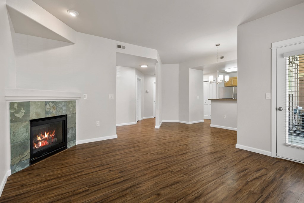 a living room with a fireplace and a door into a kitchen