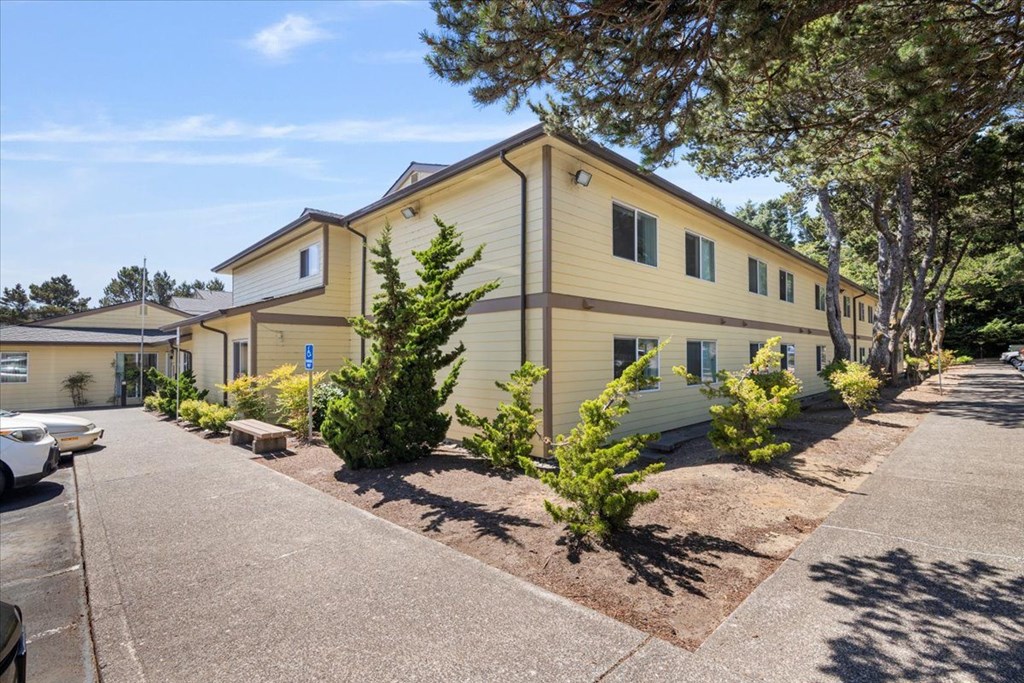A yellow building with a parking lot in front.
