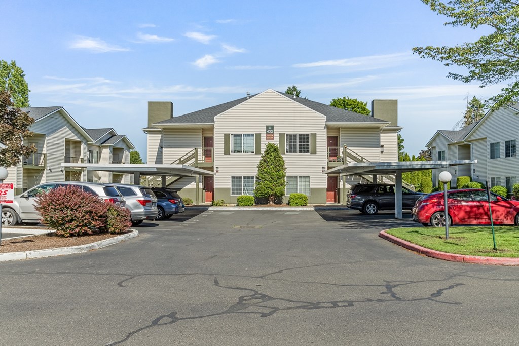 A parking lot in front of a building with cars parked.