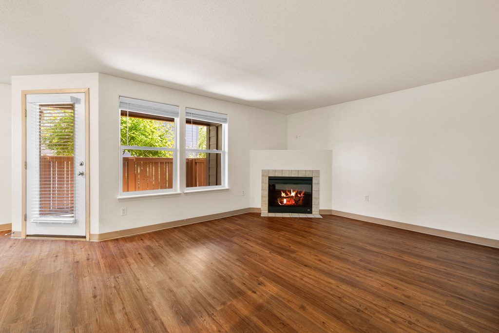 an empty living room with a fireplace and wooden floors