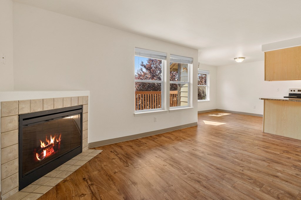 a living room with a fireplace and a kitchen with a window