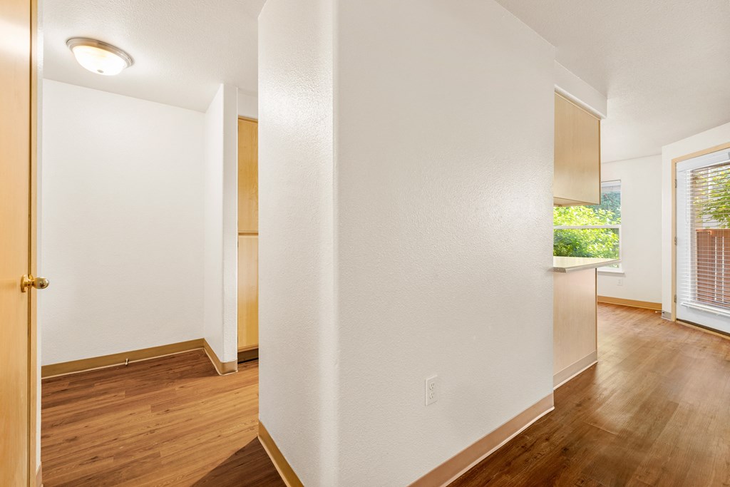 the living room and dining room of an apartment with wood flooring and a window