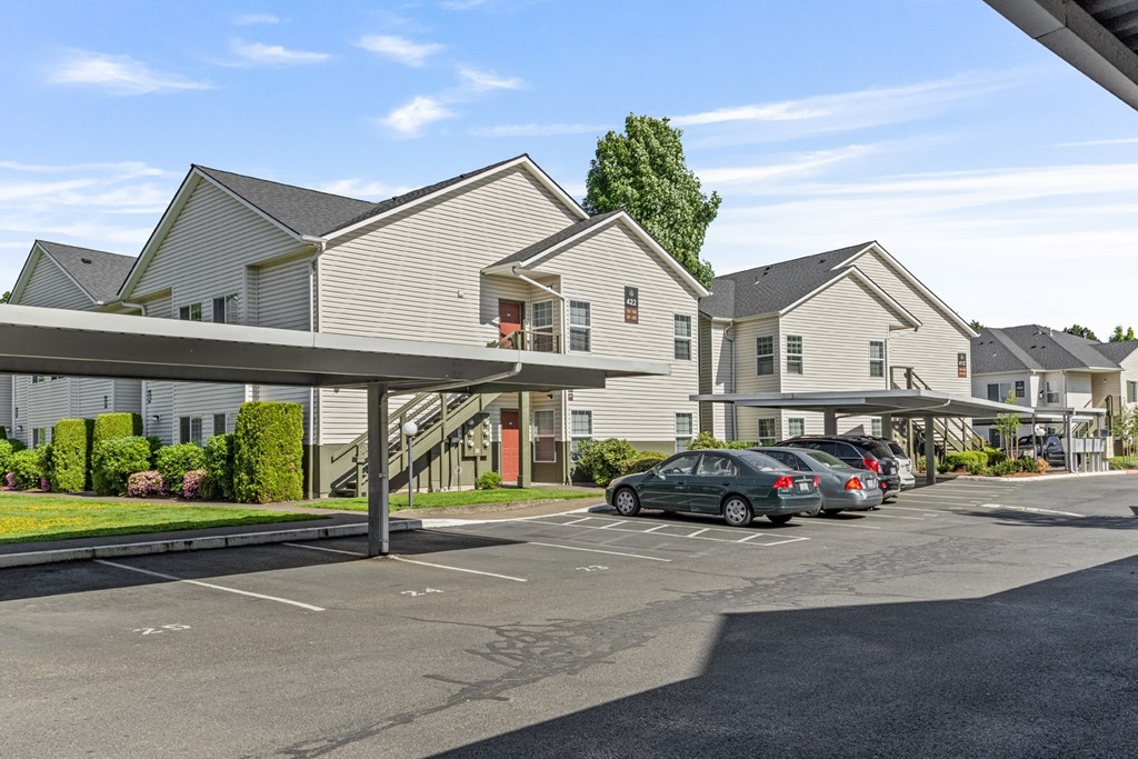 A parking lot in front of a building with cars parked.