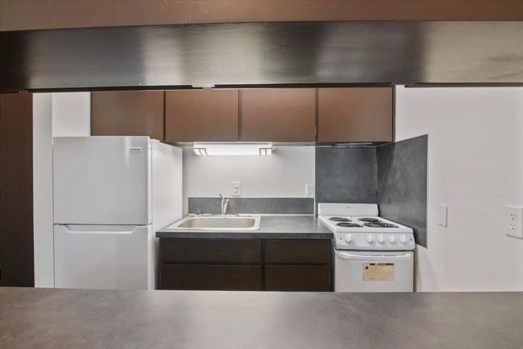 A kitchen with a white refrigerator, a stove, and a sink.