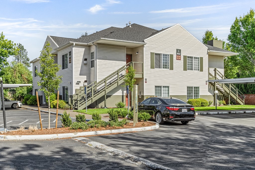 A black car is parked in front of a two-story house.