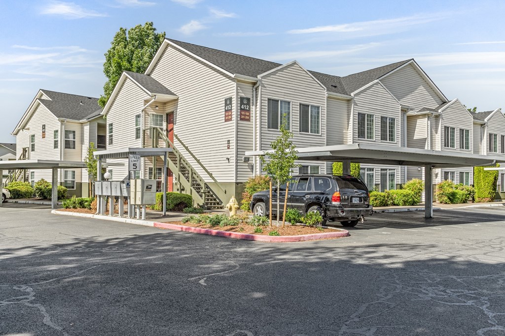 A black car is parked in a parking lot in front of a building.