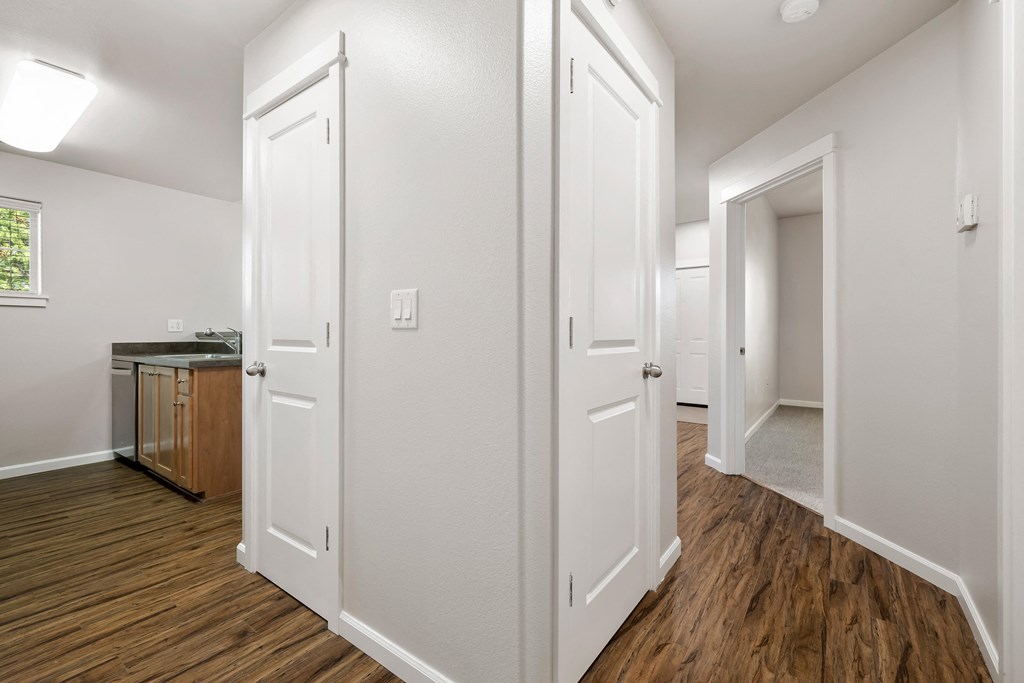 a renovated living room and kitchen with white doors and wood flooring