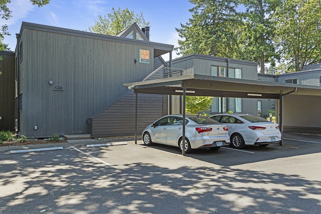 A white car is parked in front of a grey building.