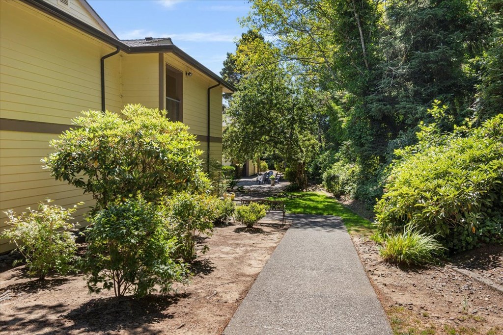 A yellow house with a brown roof and a tree in front of it.