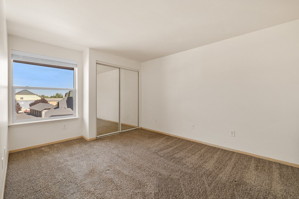 an empty room with a window and a carpeted floor