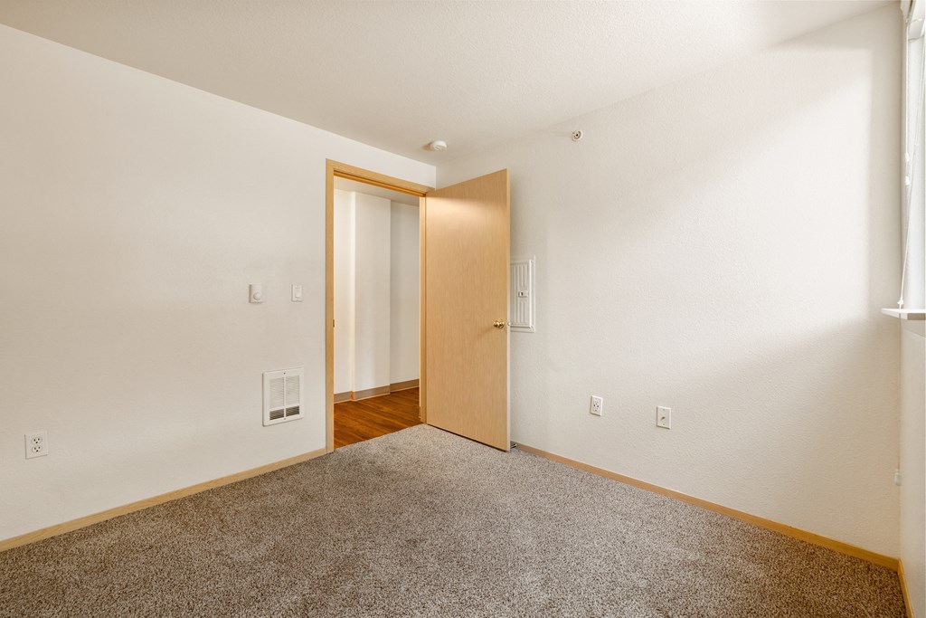 a living room with carpet and a door to a bedroom